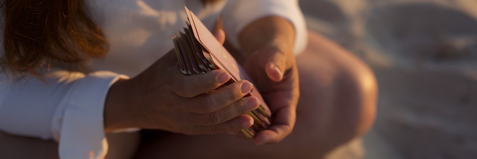 Christiane hält im Abendlicht einen aufgefächerten Stapel Tarotkarten in den Händen.